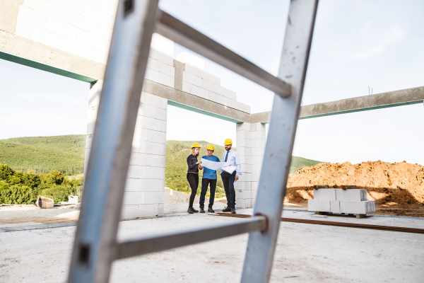 Architect, civil engineer and worker looking at plans and blueprints, discussing issues at the construction site.