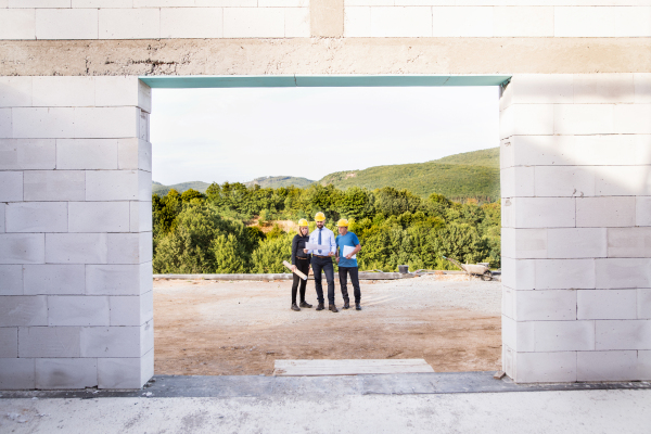 Architect, civil engineer and worker looking at plans and blueprints, discussing issues at the construction site.