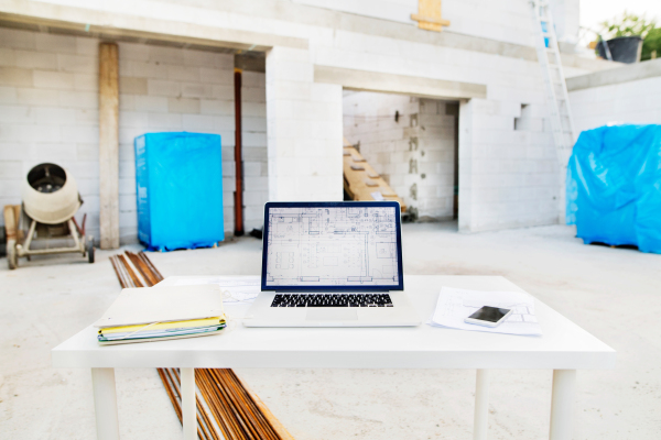 Close up of blueprints and laptop on construction site