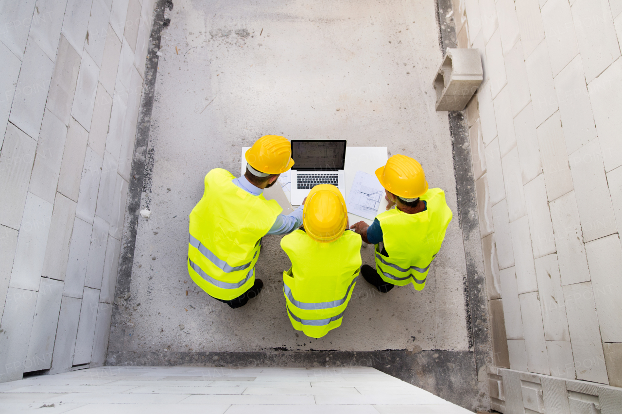 Architect, civil engineer and worker looking at plans and blueprints, discussing issues at the construction site.