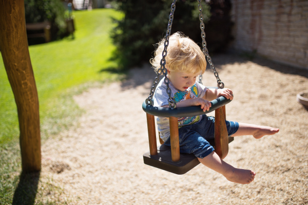 Cute little boy on the swing at the playground.