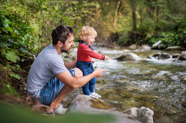 Young father with happy little boy at the river, summer day.