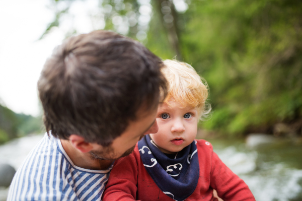 Young father with happy little boy at the river, summer day.