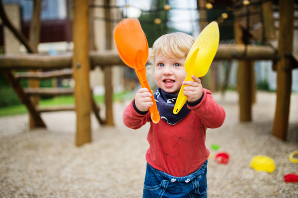 Cute toddler boy playing in the playground, summer day.