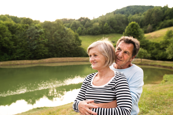 Beautiful senior couple on a walk at the lake hugging.