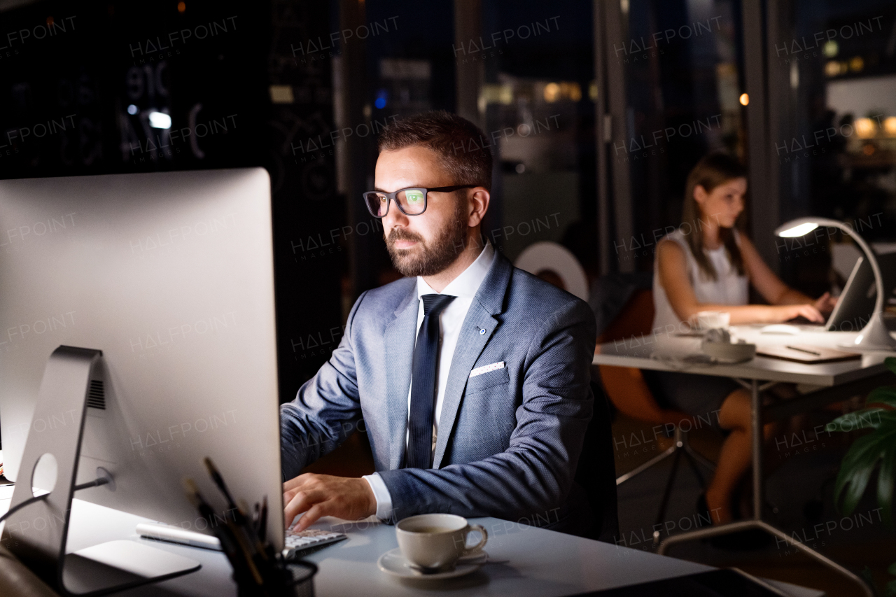 Handsome young businessman in the office with his coworker at night working late.