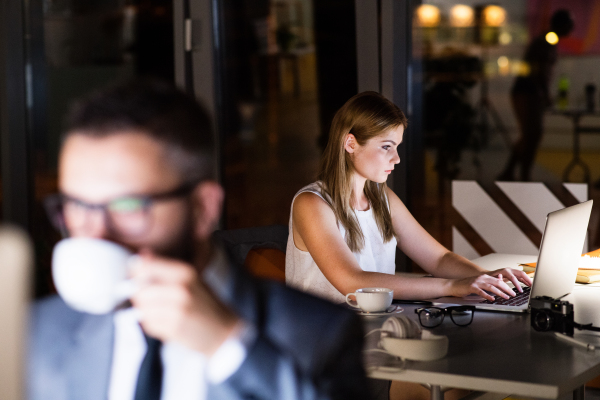 Two young businesspeople in the office at night working late.