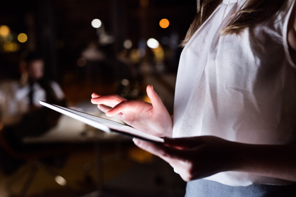 Unrecognizable young businesswoman with tablet working late at night.