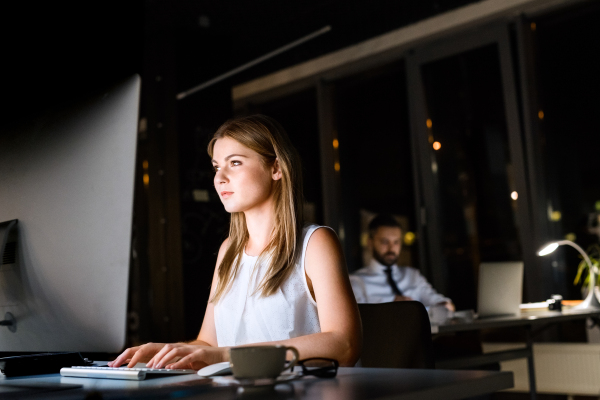 Beautiful young businesswoman in the office with her coworker at night working late.