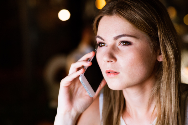 Beautiful young businesswoman with smart phone in her office late at night.