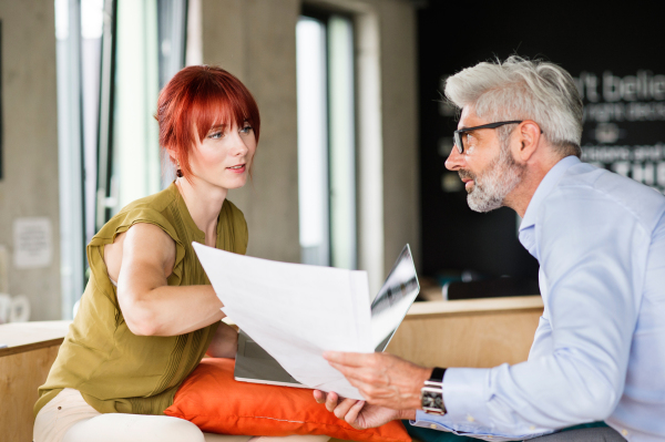 Two business people in workplace. Woman and man in creative office consulting a project together.