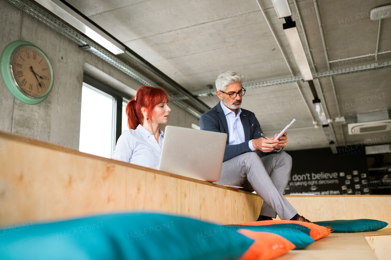 Two business people in workplace. Woman and man in creative office consulting a project together.