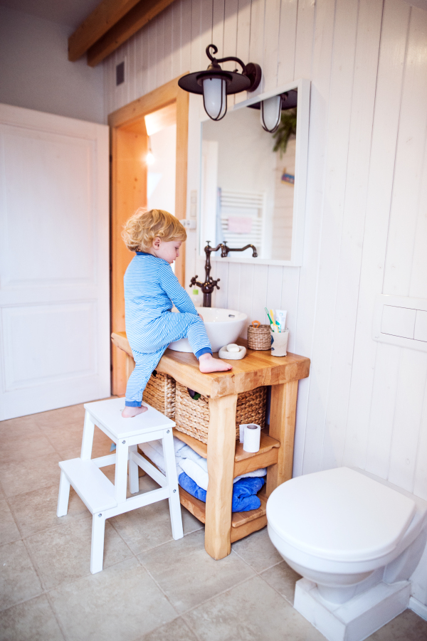 Little toddler boy climbing on a sink. Domestic accident. Dangerous situation in the bathroom.