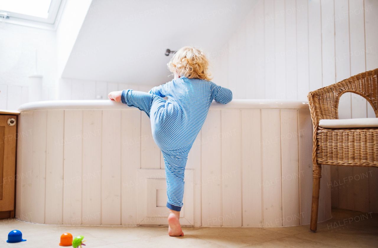 Little toddler boy climbing into a bathtub. Domestic accident. Dangerous situation in the bathroom.