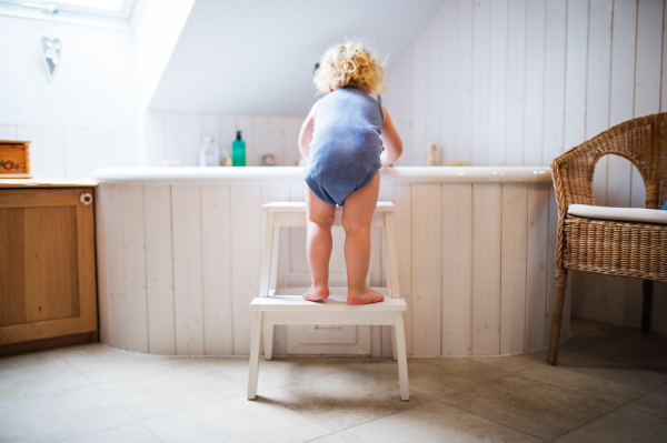 Little toddler boy getting into a bathtub. Domestic accident. Dangerous situation in the bathroom. Rear view.