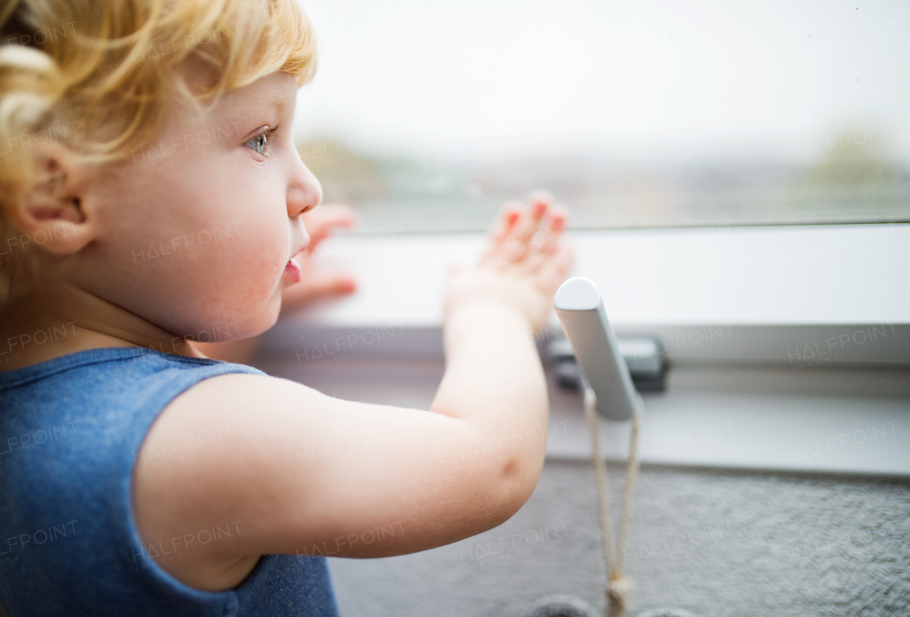 Little toddler boy opening a window. Domestic accident. Dangerous situation at home. Close up.