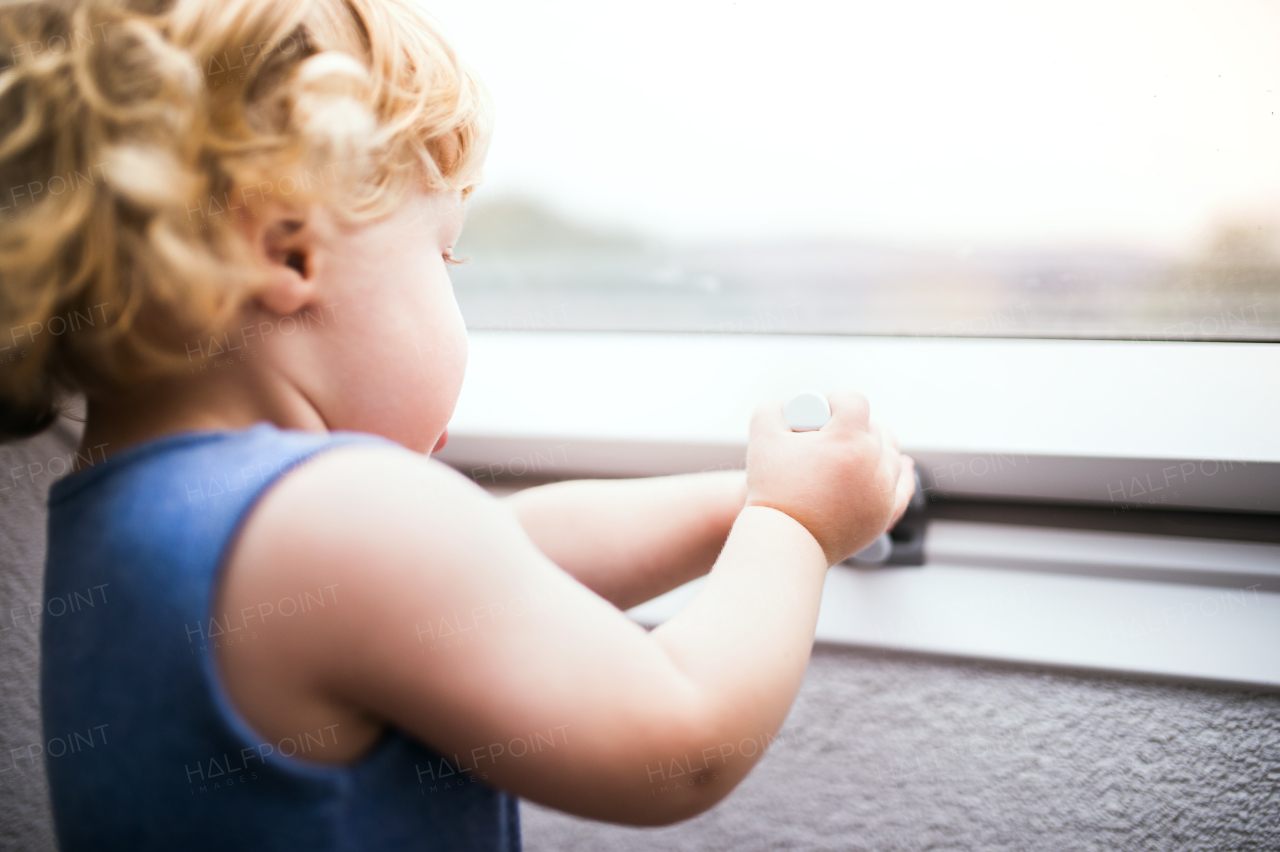 Little toddler boy trying to open a window. Domestic accident. Dangerous situation at home. Close up.