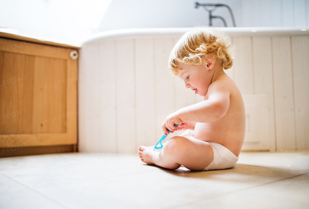 Little toddler boy holding a disposable razor. Dangerous situation at home. Domestic accident. Child safety concept.