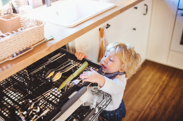 Little toddler boy opening a drawer with a knife. Domestic accident. Dangerous situation at home. Child safety concept.