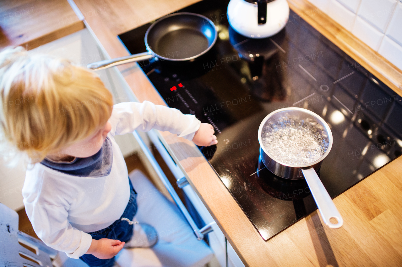 Toddler boy in a dangerous situation at home. Domestic accident. Child safety concept. Top view.