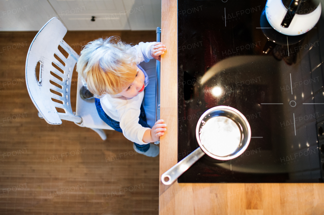 Toddler boy in a dangerous situation at home. Domestic accident. Child safety concept. Top view.