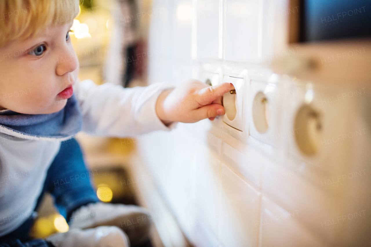 Little toddler putting fingers in a power socket. Domestic accident. Dangerous situation at home. Child safety concept.