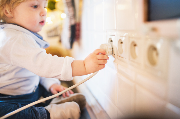 Little toddler boy playing with a plug. Domestic accident. Dangerous situation at home. Child safety concept.