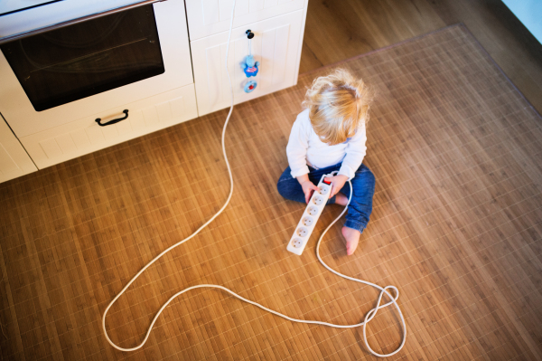 Little toddler boy playing with a plug. Domestic accident. Dangerous situation at home. Child safety concept. Top view.