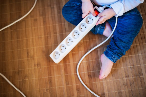 Unrecognizable little toddler boy playing with a plug. Domestic accident. Dangerous situation at home. Child safety concept. Top view.