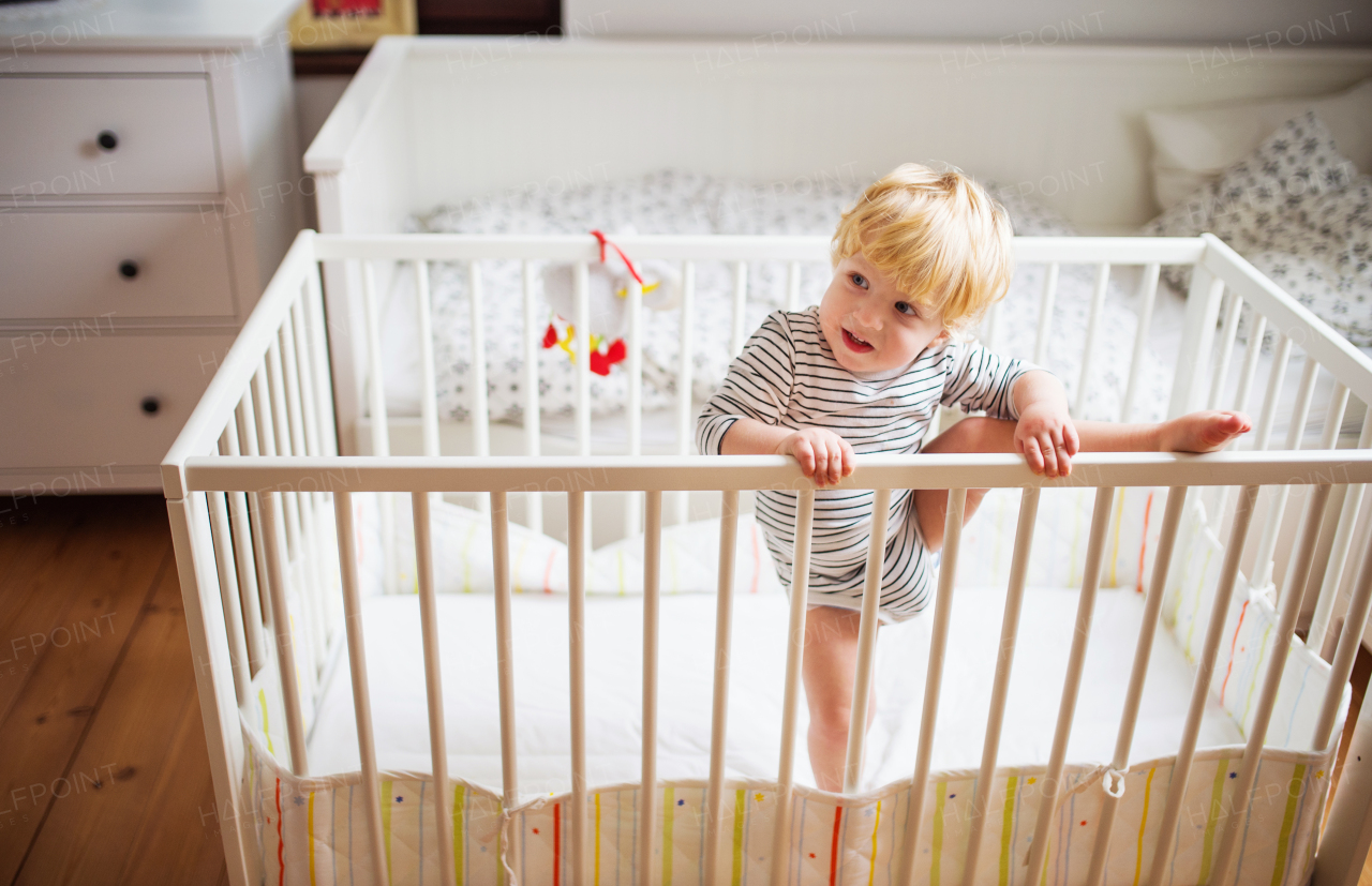 A little toddler boy getting out of a cot. Domestic accident. Dangerous situation at home.