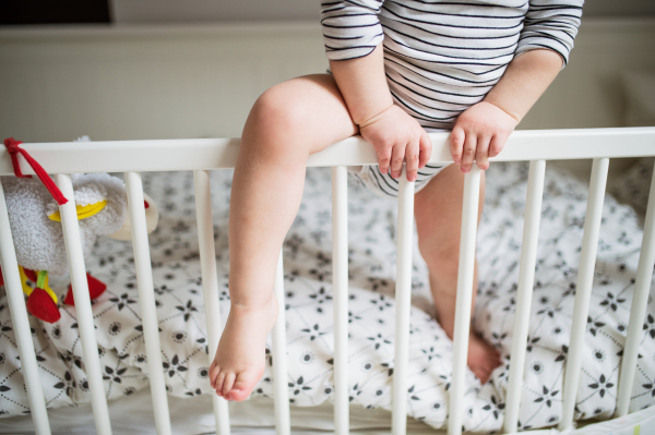 Unrecognizable little toddler boy getting out of a cot. Domestic accident. Dangerous situation at home.