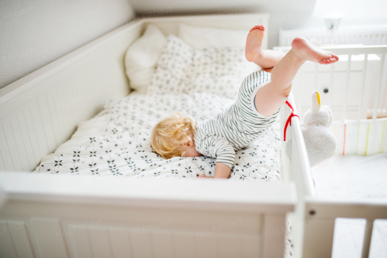 Little toddler boy getting out of a cot. Domestic accident. Dangerous situation at home.