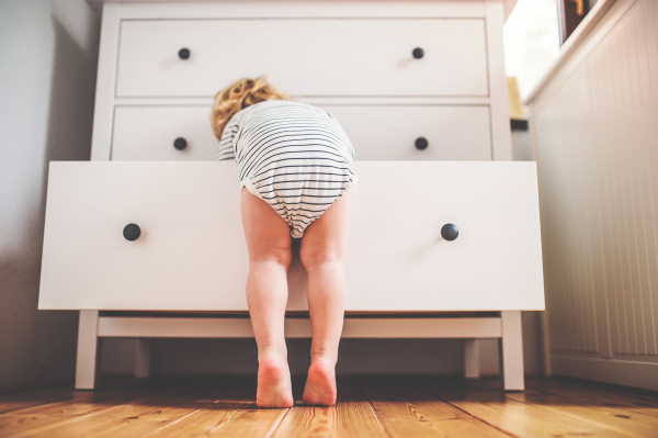 Little toddler boy opening a drawer. Domestic accident. Dangerous situation at home. Rear view.