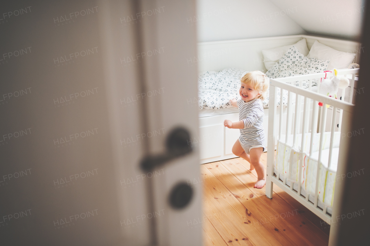 Cute happy toddler boy running in a bedroom.