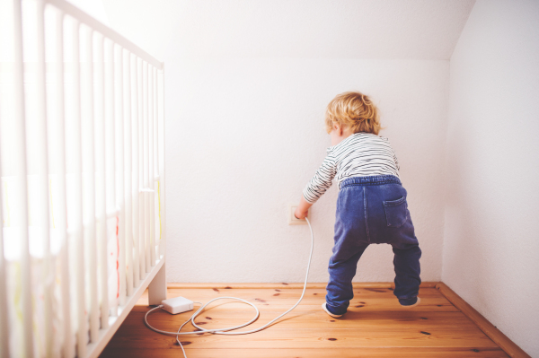 Little toddler playing with a plug. Domestic accident. Dangerous situation at home. Rear view.