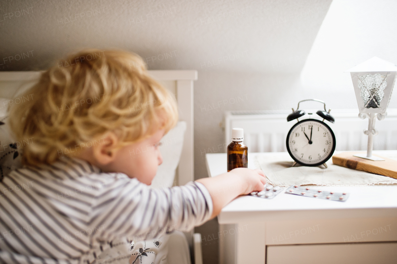 Little toddler playing with pills. Domestic accident. Dangerous situation at home.