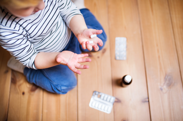 Little toddler playing with pills. Domestic accident. Dangerous situation at home. Top view.