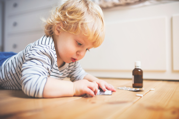 Little toddler playing with pills. Domestic accident. Dangerous situation at home.