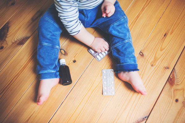 Unrecognizable little toddler playing with pills. Domestic accident. Dangerous situation at home. Top view.