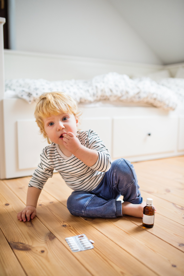 Little toddler playing with pills. Domestic accident. Dangerous situation at home.