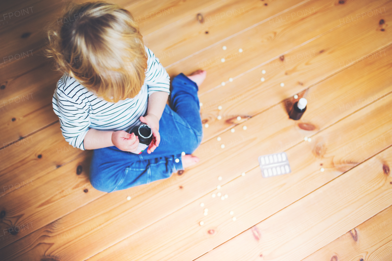 Little toddler playing with pills. Domestic accident. Dangerous situation at home. Top view.