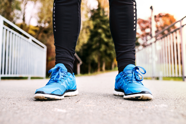 Legs of young runner standing on an asphalt path. Unrecognizable trail runner training for cross country running.