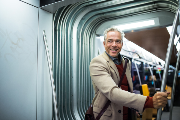 Mature handsome businessman with smartphone travelling by tram in city of Prague.