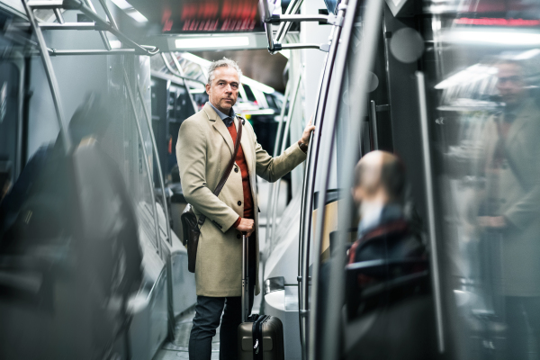 Mature handsome businessman with suitcase travellling by subway in city of Prague. Copy space.