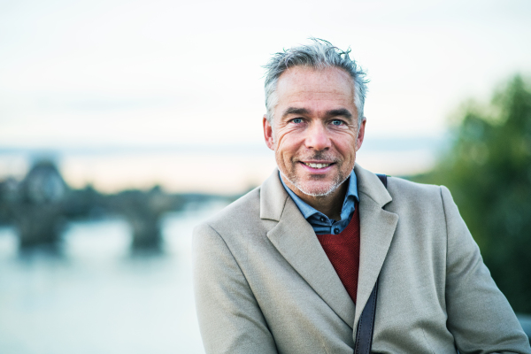 Mature handsome businessman standing by river Vltava in city of Prague. Copy space.