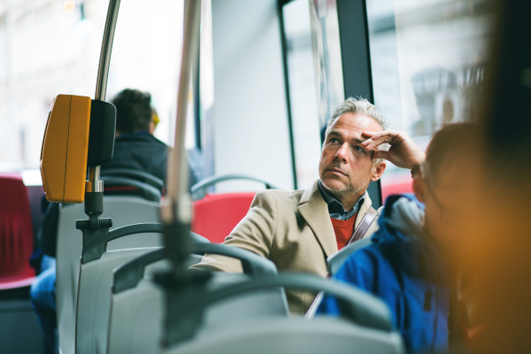 Tired mature handsome businessman travellling by bus in city of Prague. Copy space.