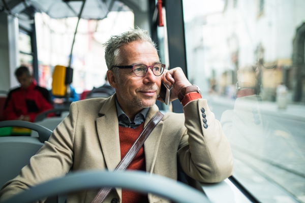 Tired mature handsome businessman travellling by bus in city of Prague. Copy space.