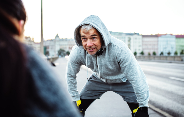 A fit sporty couple runners stretching outdoors on the streets of Prague city.