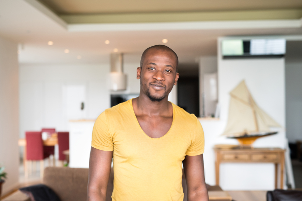 Young handsome afro-american man in yellow t-shirt at home.