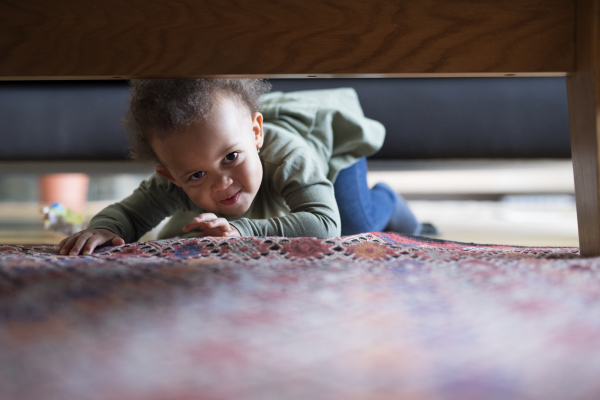 Little girl crawling at home on carpet, having fun.